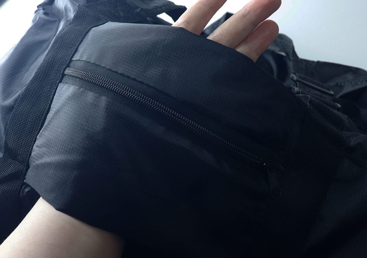 手でバッグのアウトポケットを広げスーツケースに通せる部分を見せる