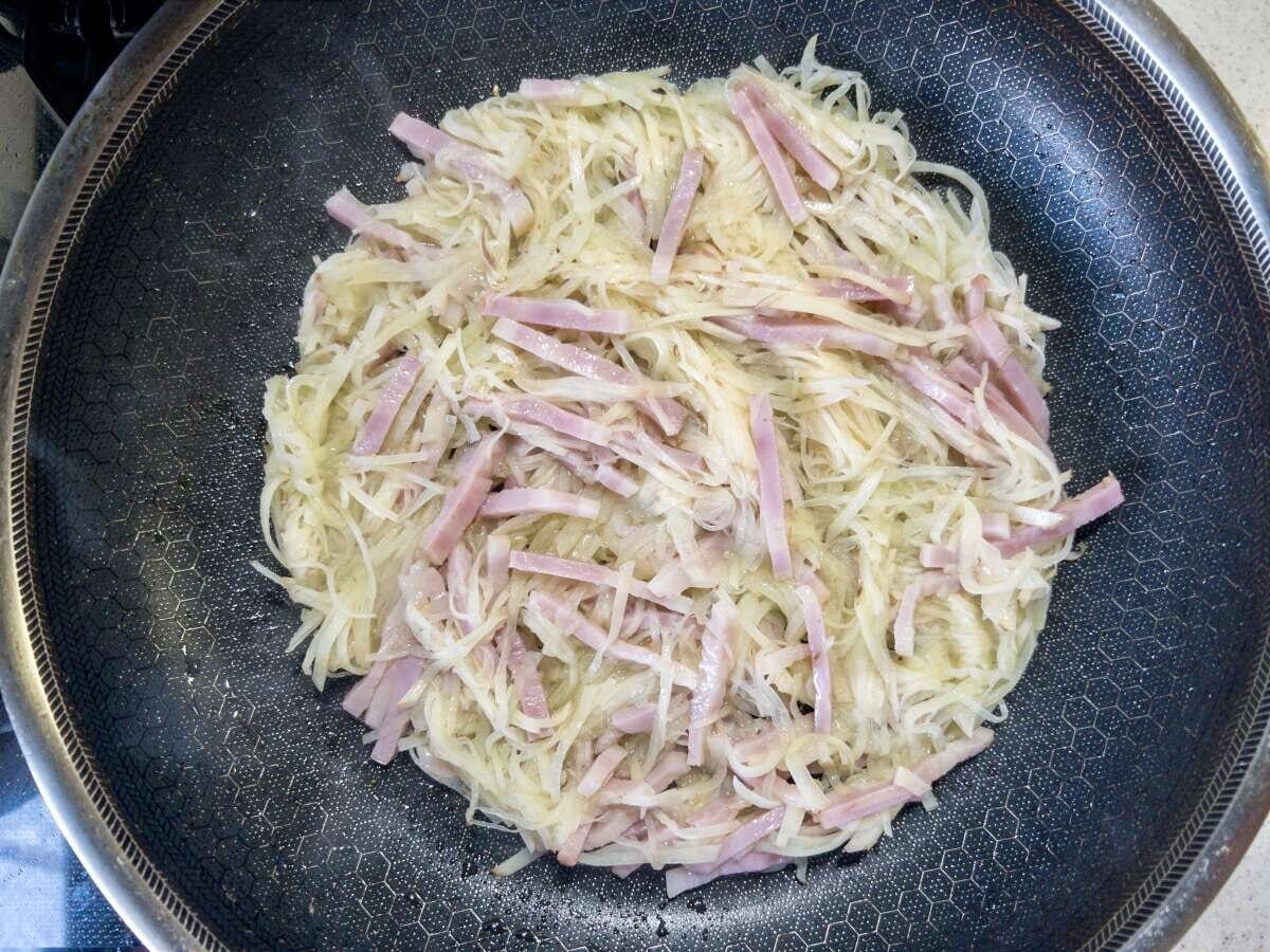 フライパンで新じゃがいもとベーコンの生地を丸く広げて焼き始めたところ