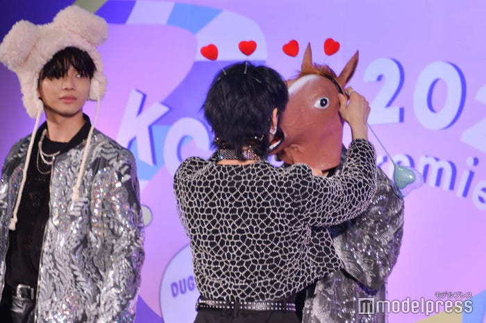 浦野秀太の被り物を付け直す佐野文哉 (C)モデルプレス