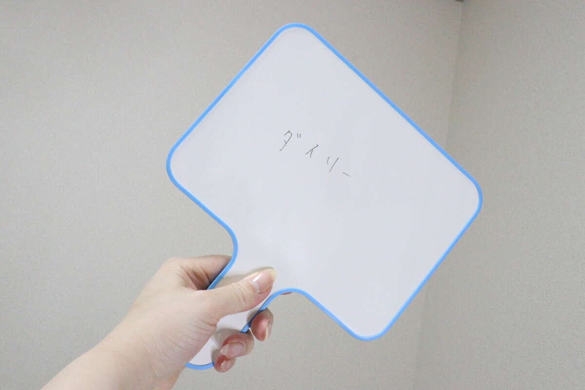 女性が「ダースリー」と書かれたホワイトボードを掲げる