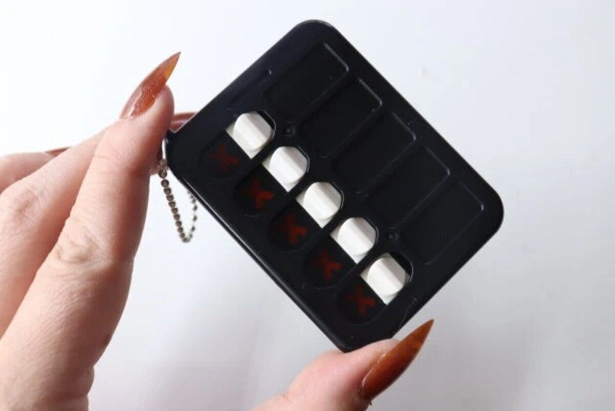 女性の指が黒いチェッカーキーホルダーを持っている