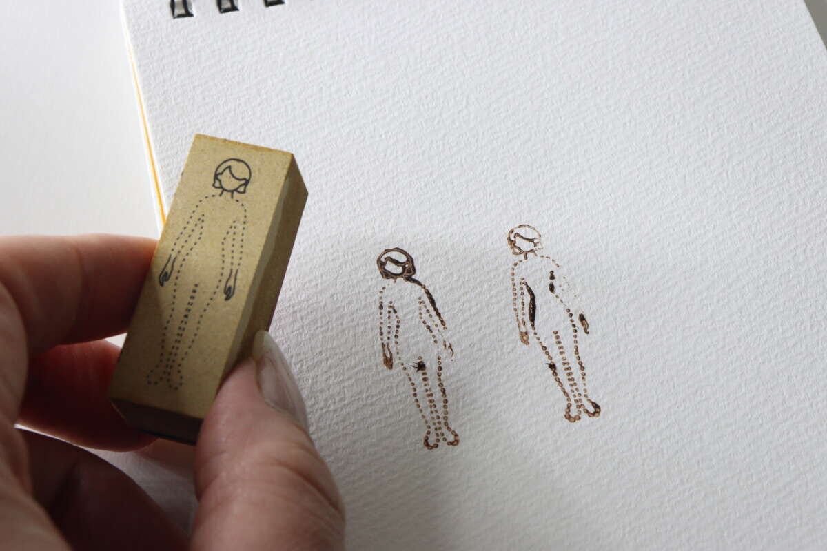 手帳の紙にブラウンのインクで女性のスタンプを押している瞬間