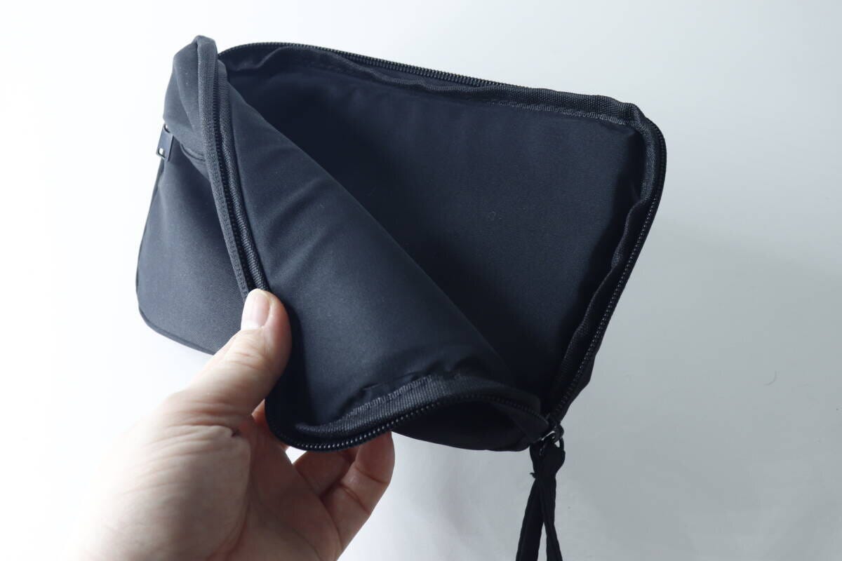 手でポーチのファスナーを開けクッション材を見せている