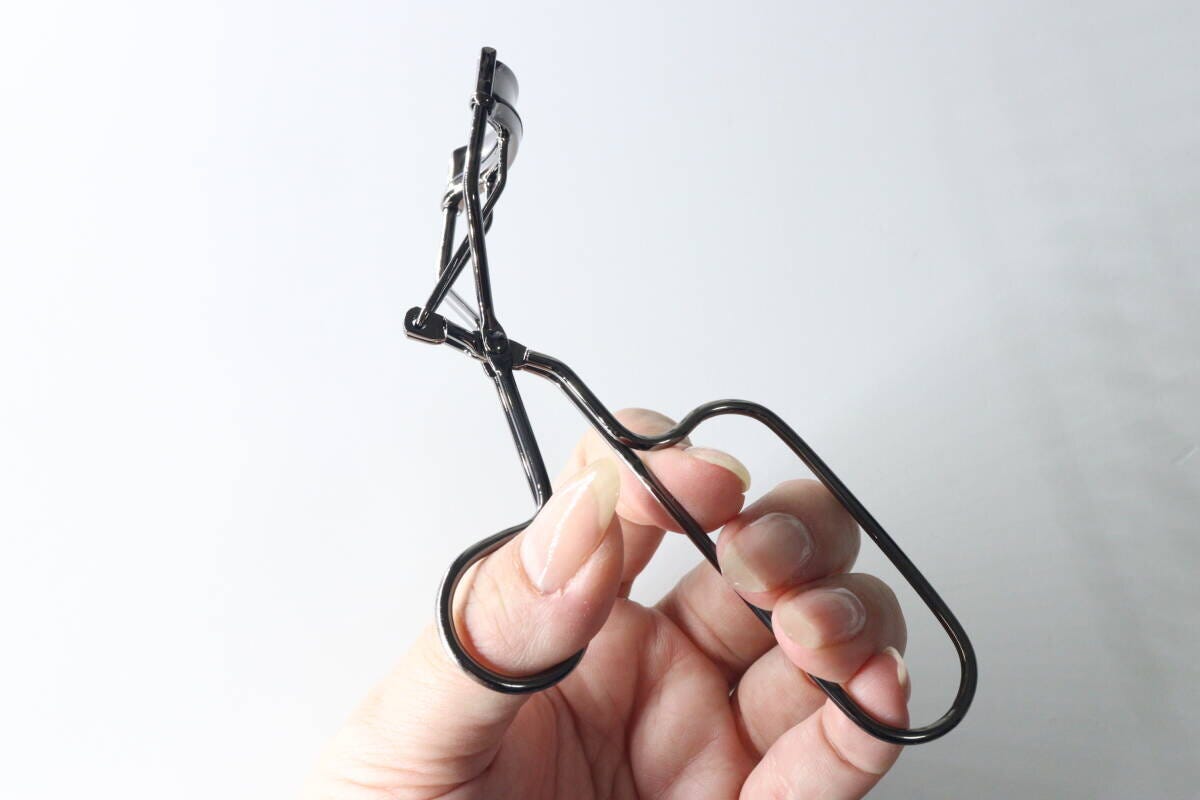 女性が長い持ち手のビューラーを指全体で握っている様子