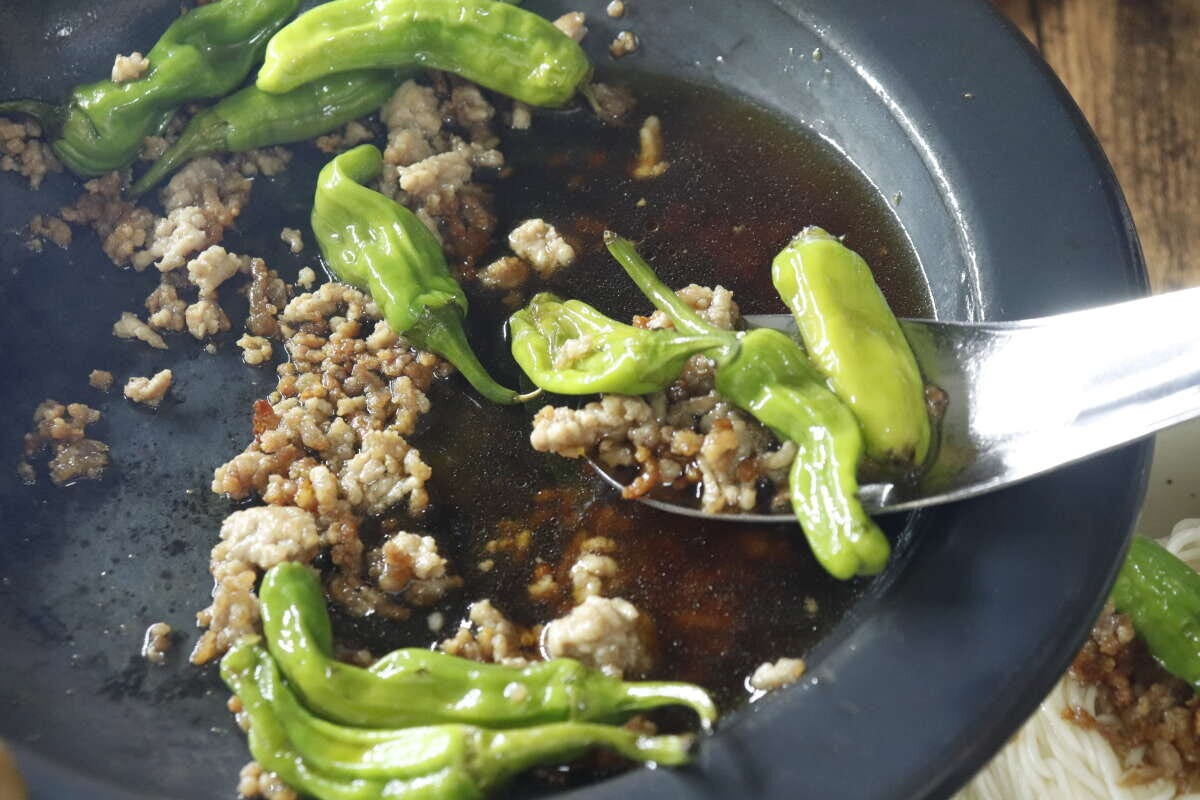 ひき肉とピーマンの炒め物をレンゲスプーンですくう様子 ひき肉とピーマンの炒め物をレンゲスプーンですくう様子