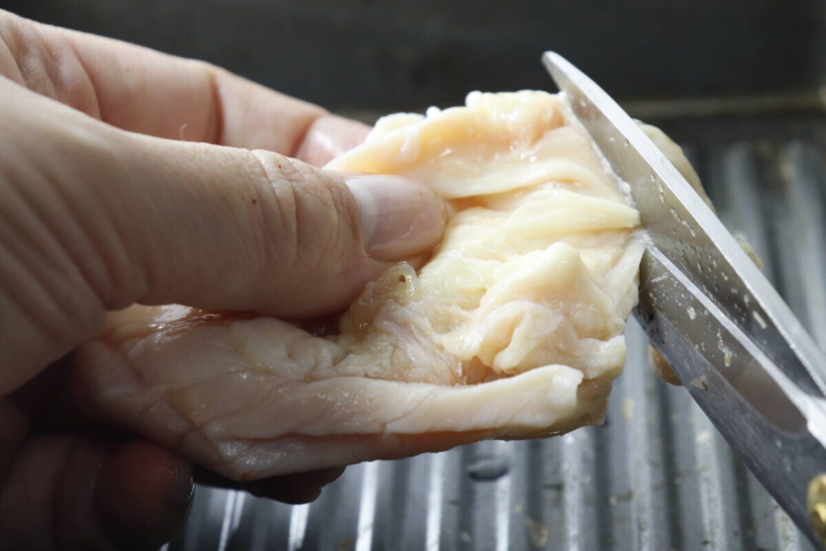 厚刃キッチンハサミで鶏皮を細かくカットしている手元