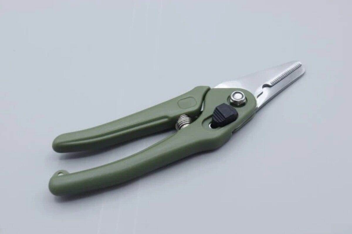グリーンのグリップと銀色の刃のダイソー園芸万能ハサミが開いた状態で置かれている グリーンのグリップと銀色の刃のダイソー園芸万能ハサミが開いた状態で置かれている