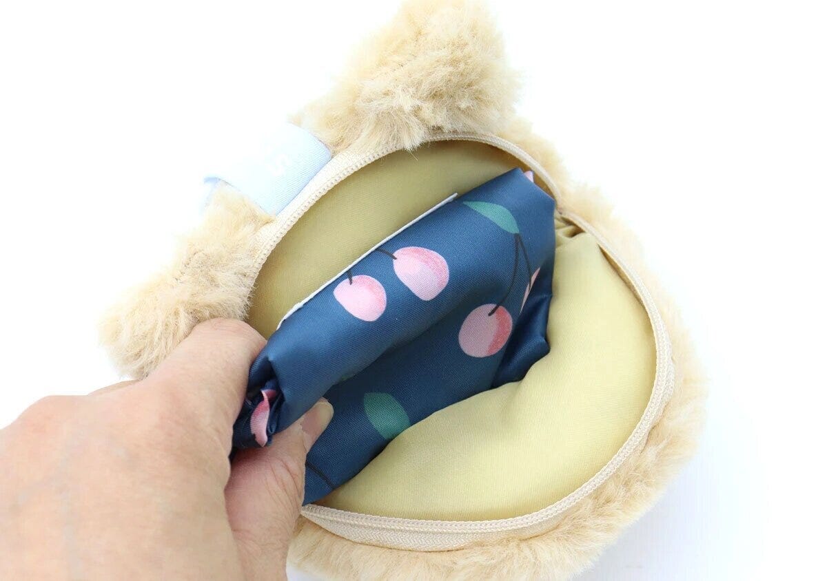モンチッチのぬいぐるみチャームの中にたたんだエコバッグを収納している手元