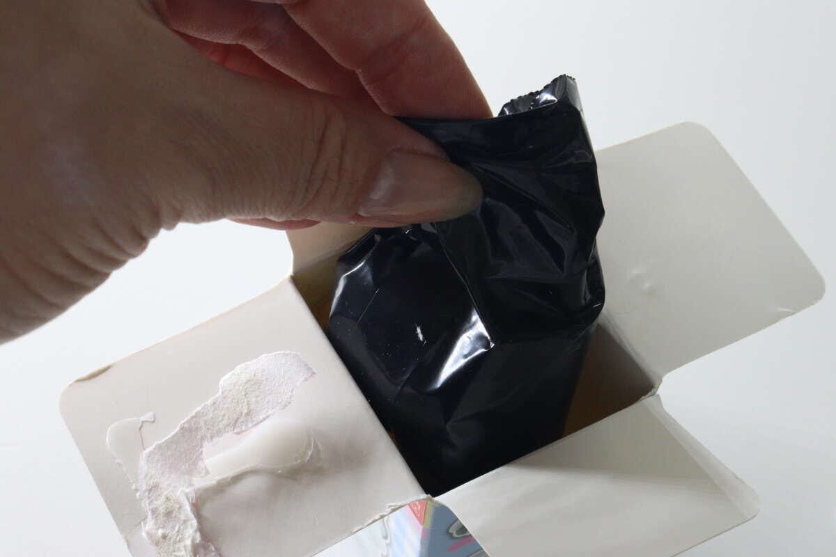 開封されたパッケージから中身の黒い袋を取り出す様子