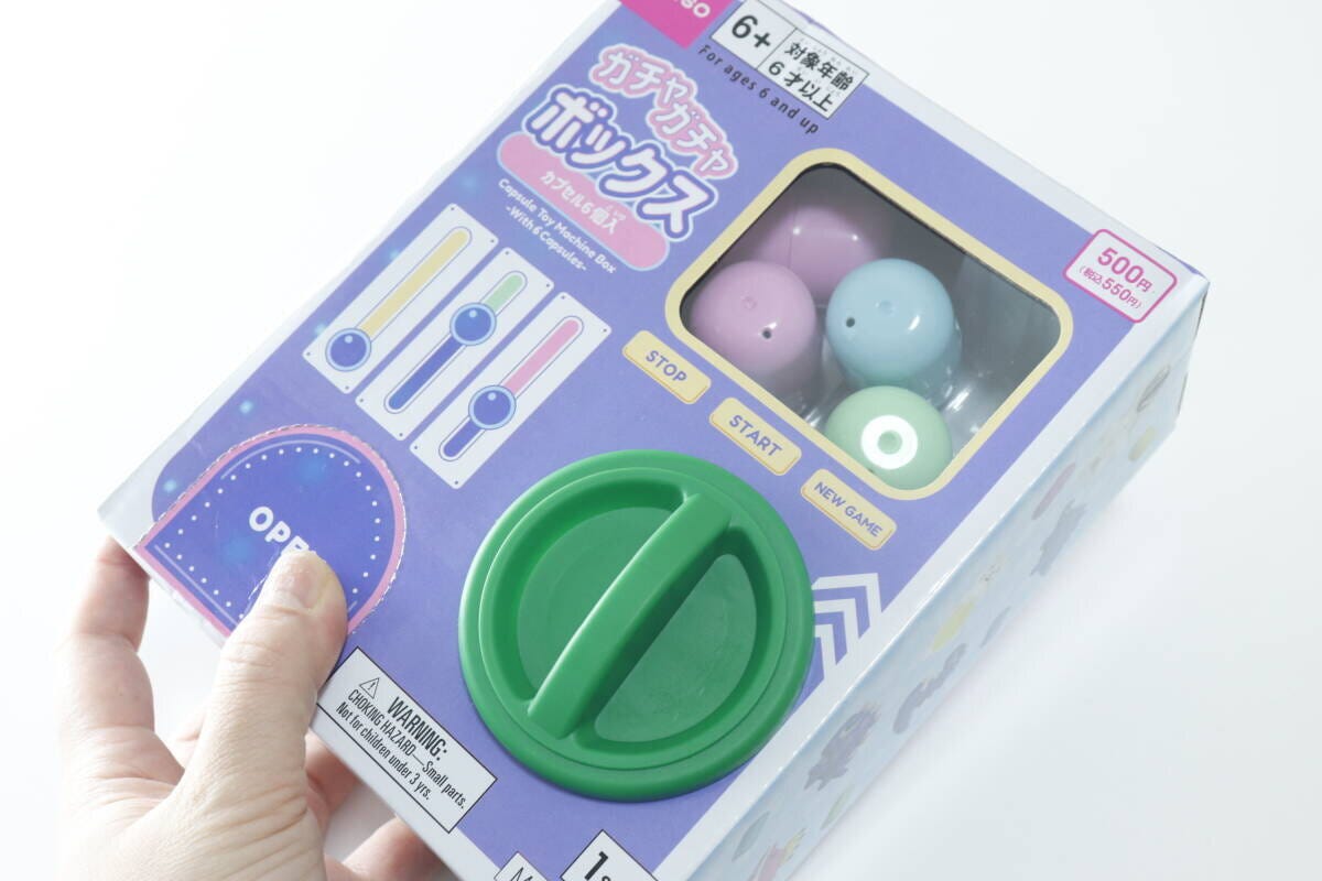 女性がダイソーのガチャガチャボックスを手に持っている