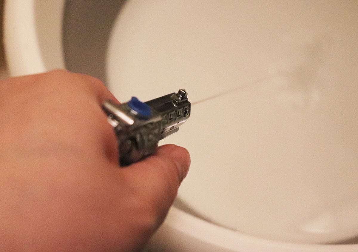 手に持った水鉄砲キーホルダーから発射された水が白いシンクに当たる