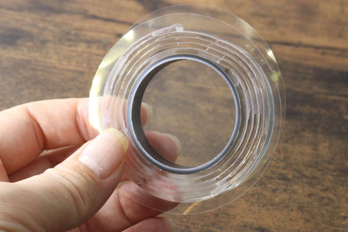 指で持った透明な強力両面粘着ゲルテープのロール