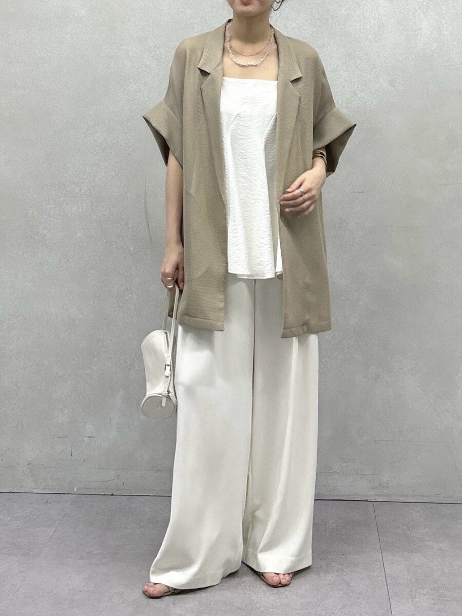 白いフレアキャミにベージュの半袖ジャケットを羽織った女性の全身 白いフレアキャミにベージュの半袖ジャケットを羽織った女性の全身