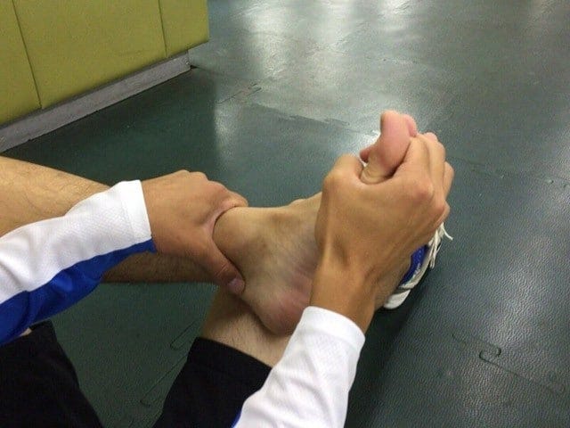 足首を保持し、足指と手指を組んで大きくまわそう