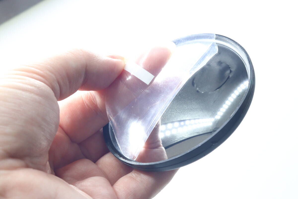 指で自転車用バックミラーの表面の保護フィルムを剥がしている様子 指で自転車用バックミラーの表面の保護フィルムを剥がしている様子