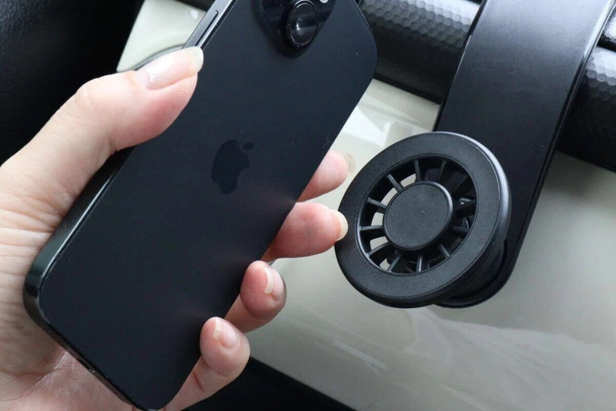 女性の手に持たれた黒いスマホと車載用ホルダーのマグネット部分 女性の手に持たれた黒いスマホと車載用ホルダーのマグネット部分
