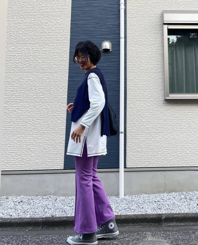 白のロンTにネイビーのニットベストを合わせ、パープルのフレアパンツ、グレーのハイカットスニーカーをコーディネート