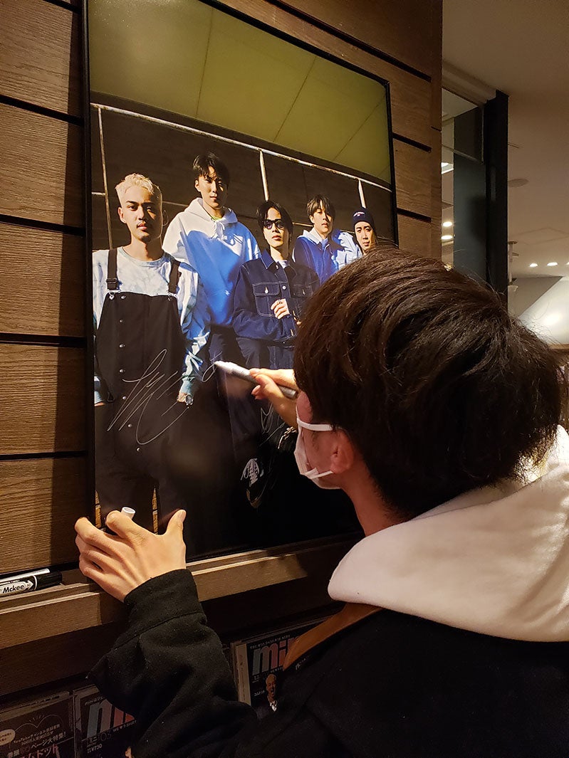 サインを書くコムドットメンバー（画像提供：宝島社）