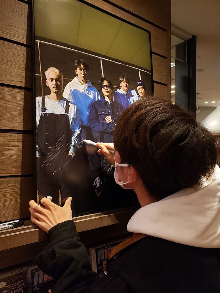 サインを書くコムドットメンバー(画像提供:宝島社)