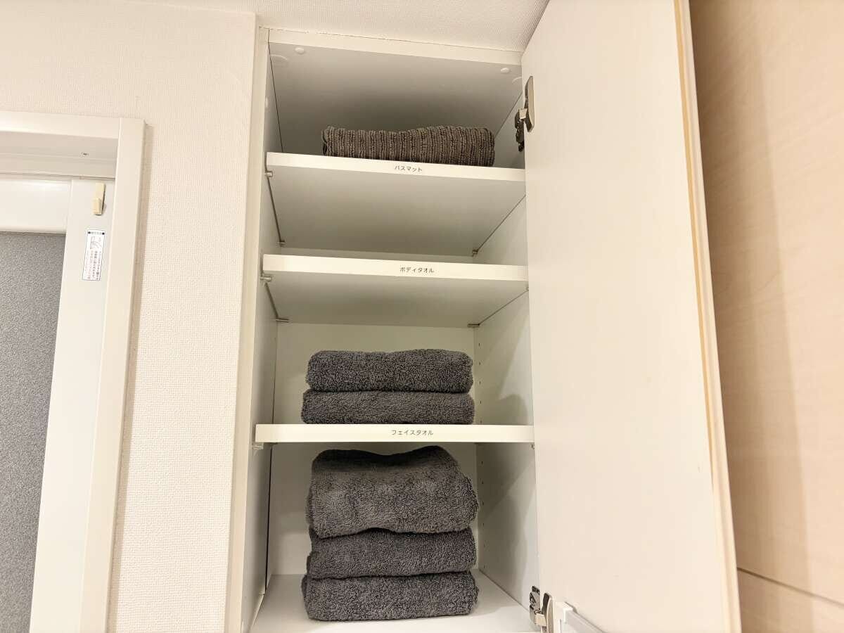 グレーで色を揃えて整えたホテルライクなタオル収納 同じ棚にグレーで色を統一したタオルがきれいにたたまれて整然と並んでいる様子