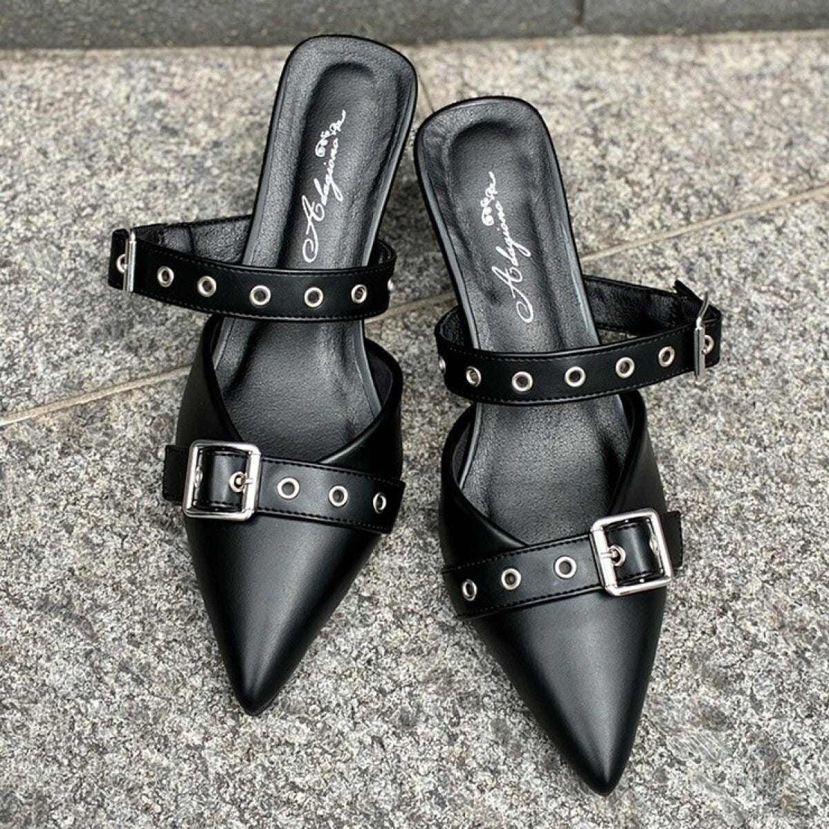 黒いポインテッドトゥのミュールパンプス。甲に2本のバックル付きベルトがある。