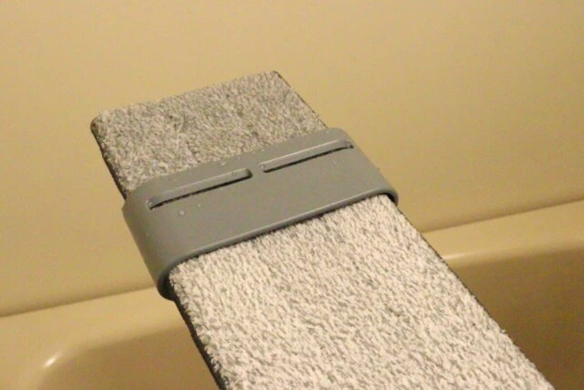 グレーのモップヘッドがバケツの縁に押し付けられ水絞りされている様子