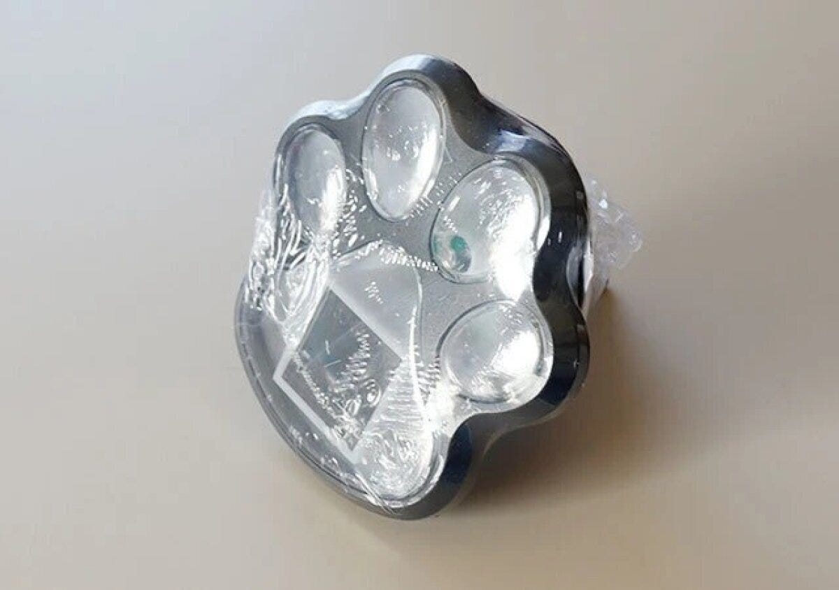 猫の肉球型をしたシルバーのソーラーガーデンライトが袋に包まれた状態で置かれている 猫の肉球型をしたシルバーのソーラーガーデンライトが袋に包まれた状態で置かれている