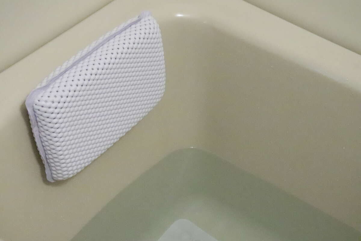 浴槽の壁に吸盤で固定された白いお風呂枕 浴槽の壁に吸盤で固定された白いお風呂枕