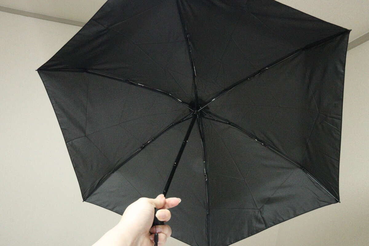 広げた状態の黒い折りたたみ傘を、下から見上げるように撮影している