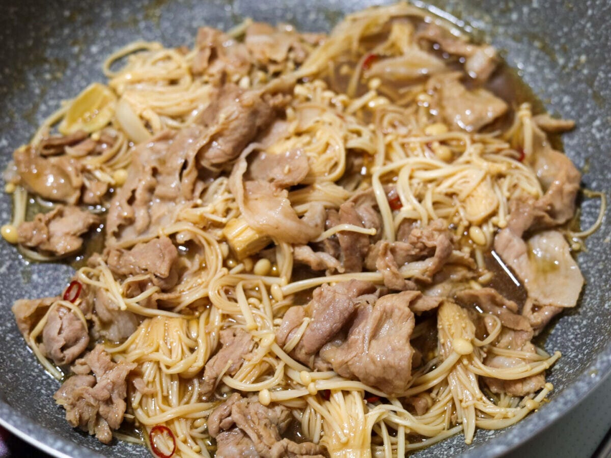 フライパンの中で豚肉とえのきが煮詰められ、全体に煮汁が絡んでいる様子 フライパンの中で豚肉とえのきが煮詰められ、全体に煮汁が絡んでいる様子