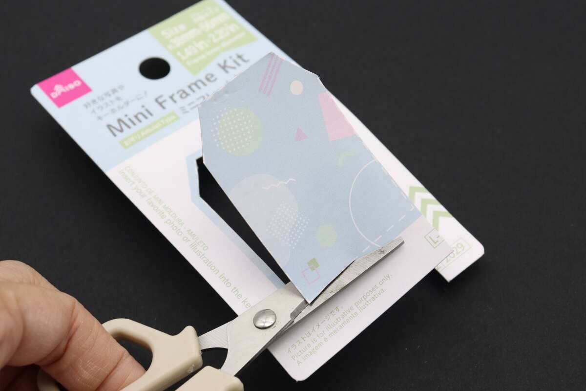 ハサミでミニフレームキットのパッケージ台紙をガイドに沿って切り抜いている手元 ハサミでミニフレームキットのパッケージ台紙をガイドに沿って切り抜いている手元
