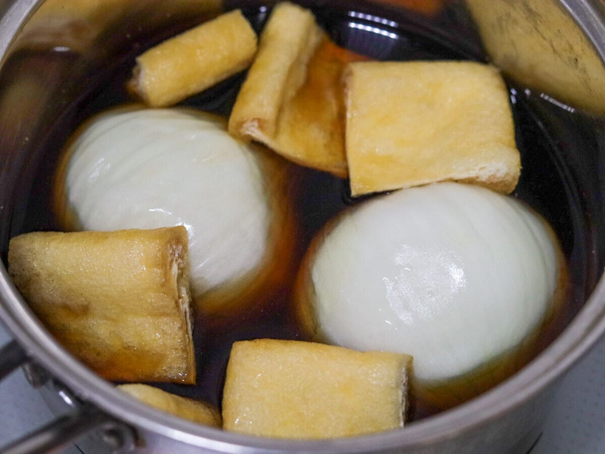 鍋に新玉ねぎと油揚げを入れて煮汁に浸した状態 鍋に新玉ねぎと油揚げを入れて煮汁に浸した状態