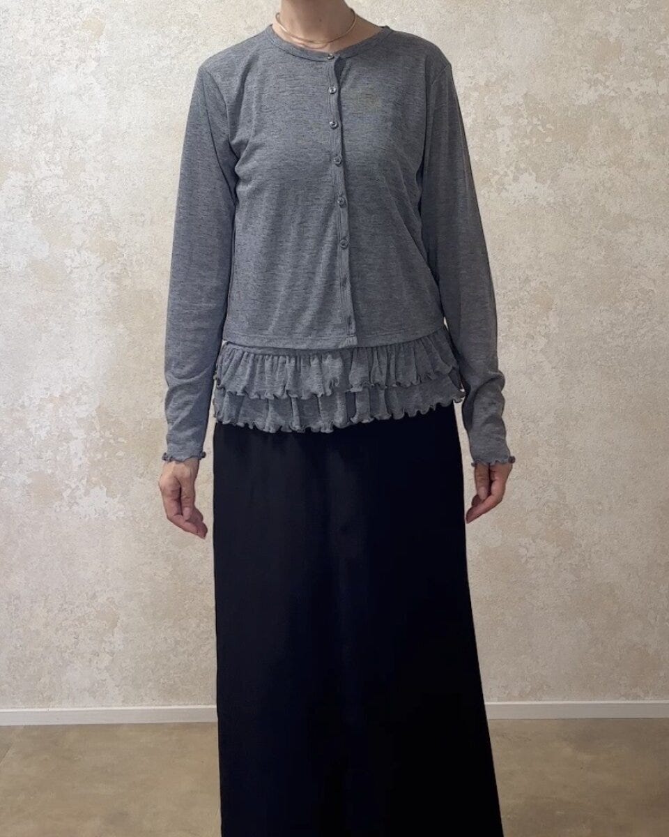 グレーのカーディガンと黒のロングスカートを着用した女性の全身
