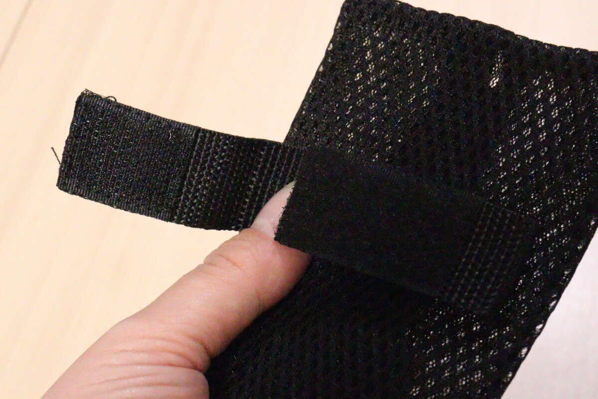 ポーチの裏側にある面ファスナーを指で開いて見せている様子