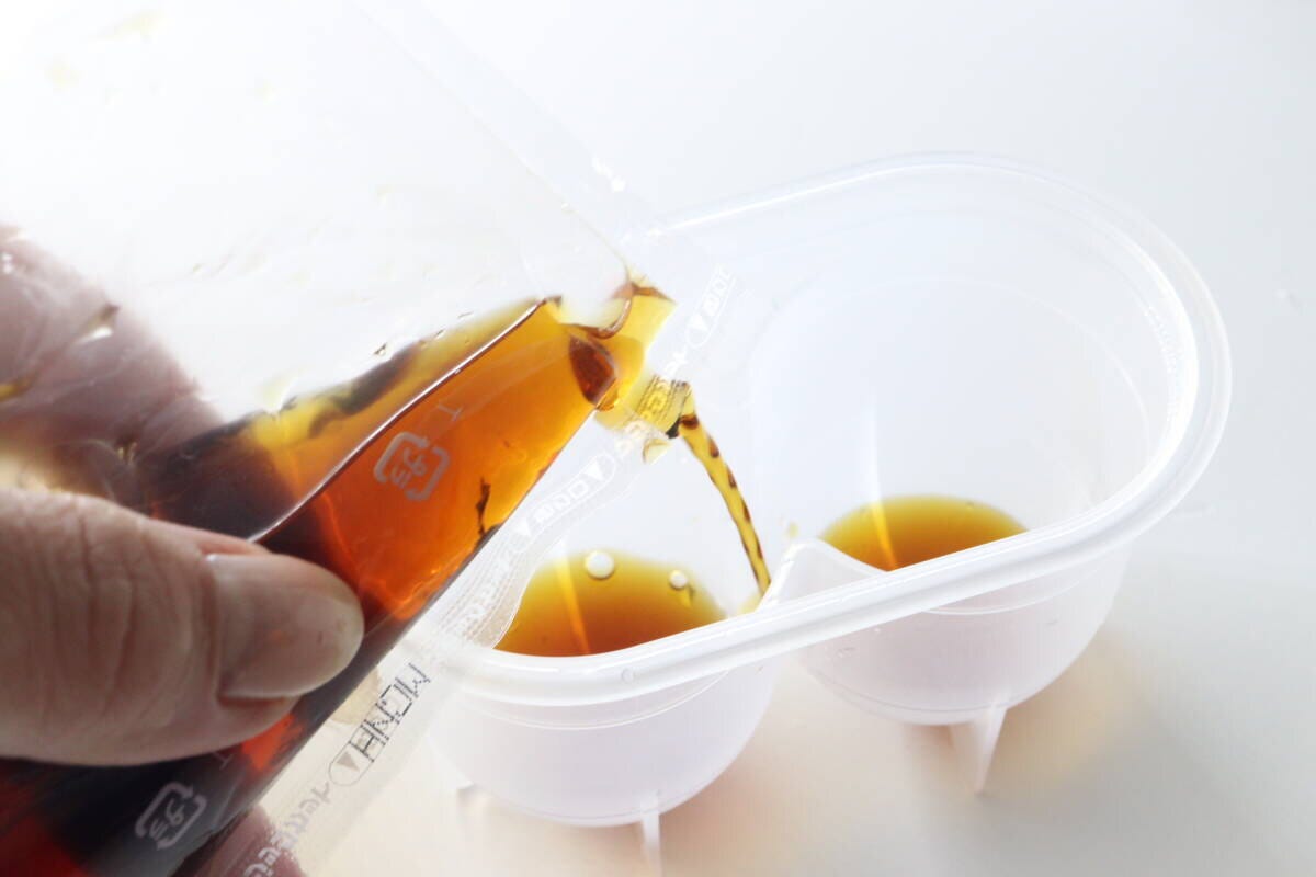 味玉名人の容器にめんつゆを注ぎ入れている手元 味玉名人の容器にめんつゆを注ぎ入れている手元