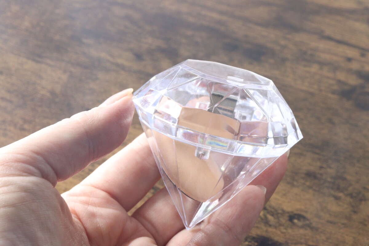 女性の手がダイヤモンド型クリアケースの蓋を開けている 女性の手がダイヤモンド型クリアケースの蓋を開けている