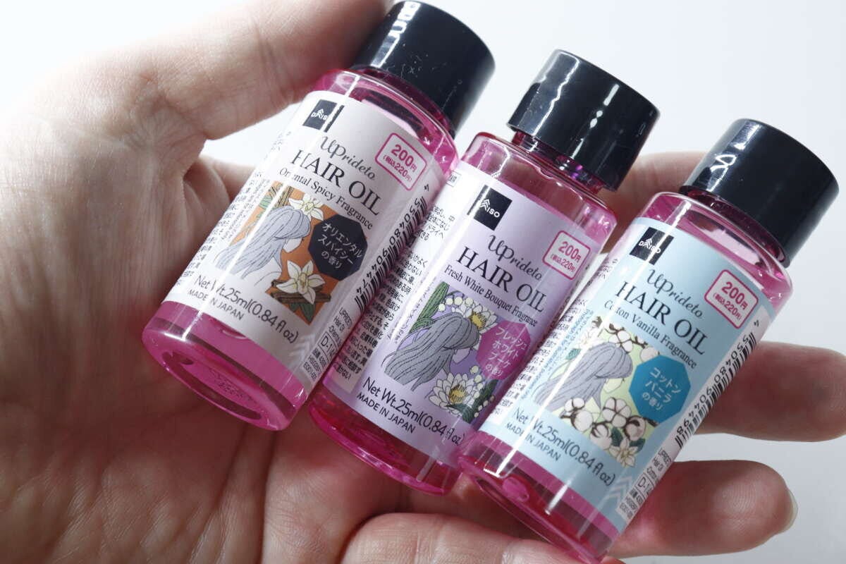 手のひらにダイソーのヘアオイル3種類を並べて持っている