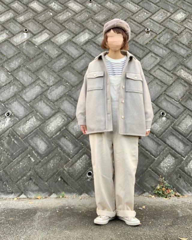 白のボーダートップスにグレーのCPOジャケットを羽織り、白のオーバーオール、スニーカー、ベージュのベレー帽をコーディネート