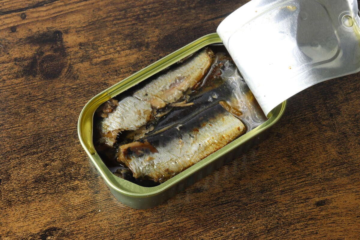 開封された「いわしオイル漬け」の缶詰が木目のテーブルに置かれ、中にはオイルに浸かったいわしが数尾見える 開封された「いわしオイル漬け」の缶詰が木目のテーブルに置かれ、中にはオイルに浸かったいわしが数尾見える