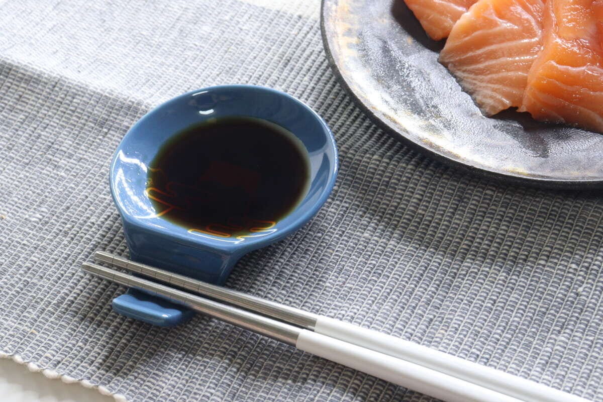 青い箸置き豆皿に醤油が入り、箸が置かれた食卓 青い箸置き豆皿に醤油が入り、箸が置かれた食卓