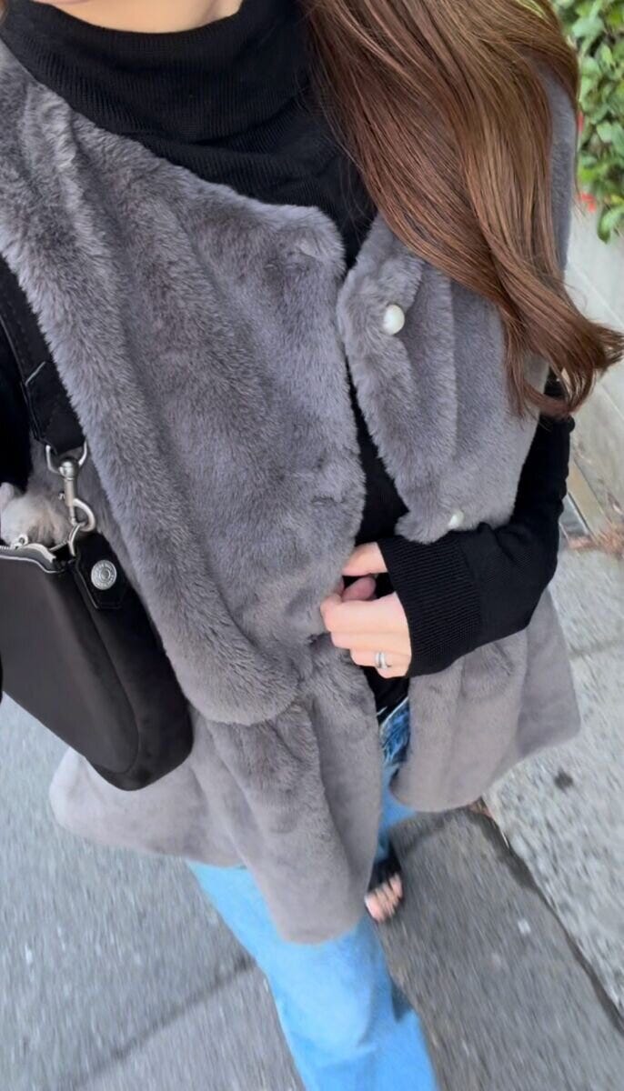 デニムパンツに黒タートルとファーベストを合わせた着こなし