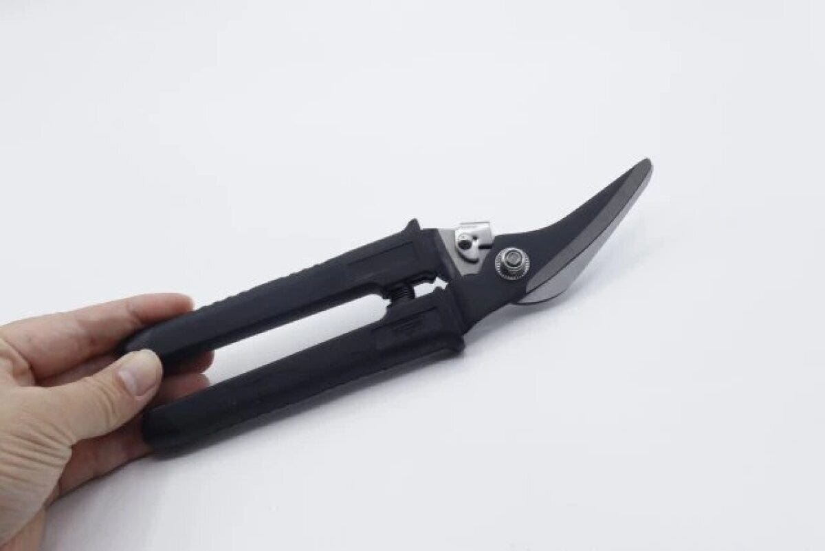 手が黒い万能ハサミを握り、刃先が上を向いている