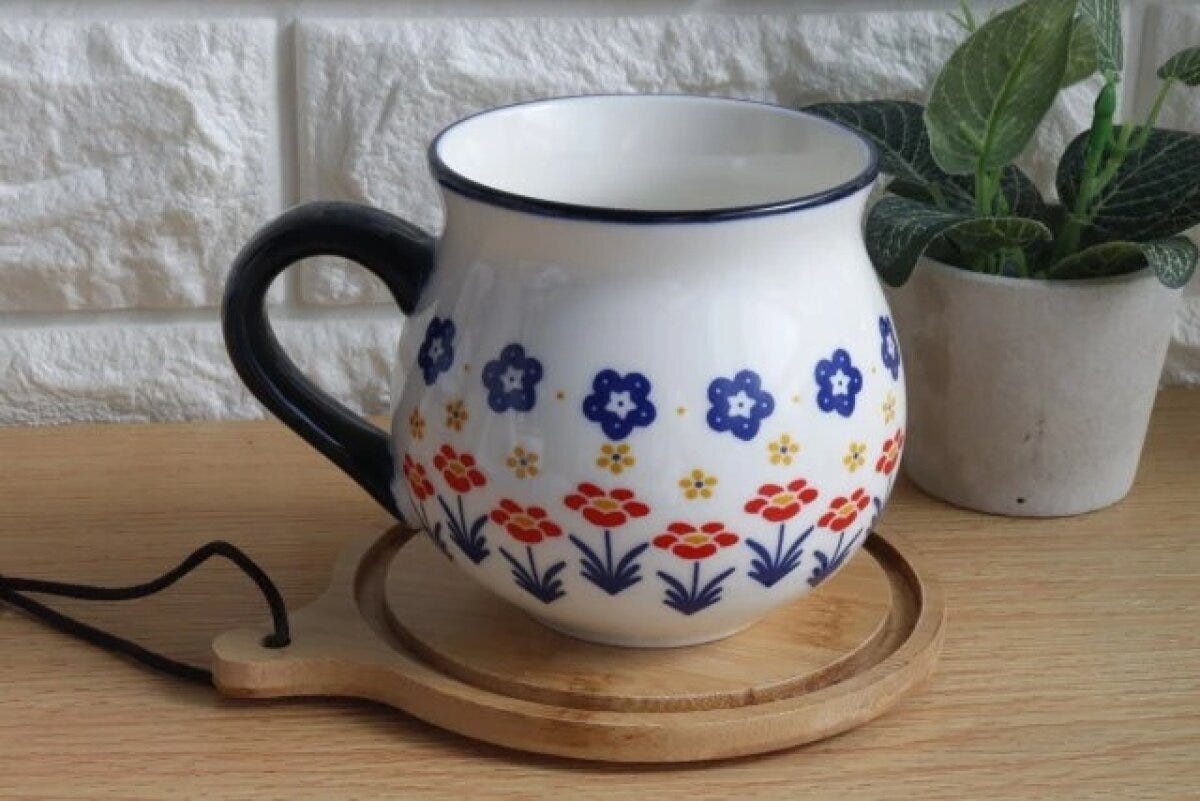 ポーリッシュ風の花柄マグカップが木製コースターに乗っている ポーリッシュ風の花柄マグカップが木製コースターに乗っている