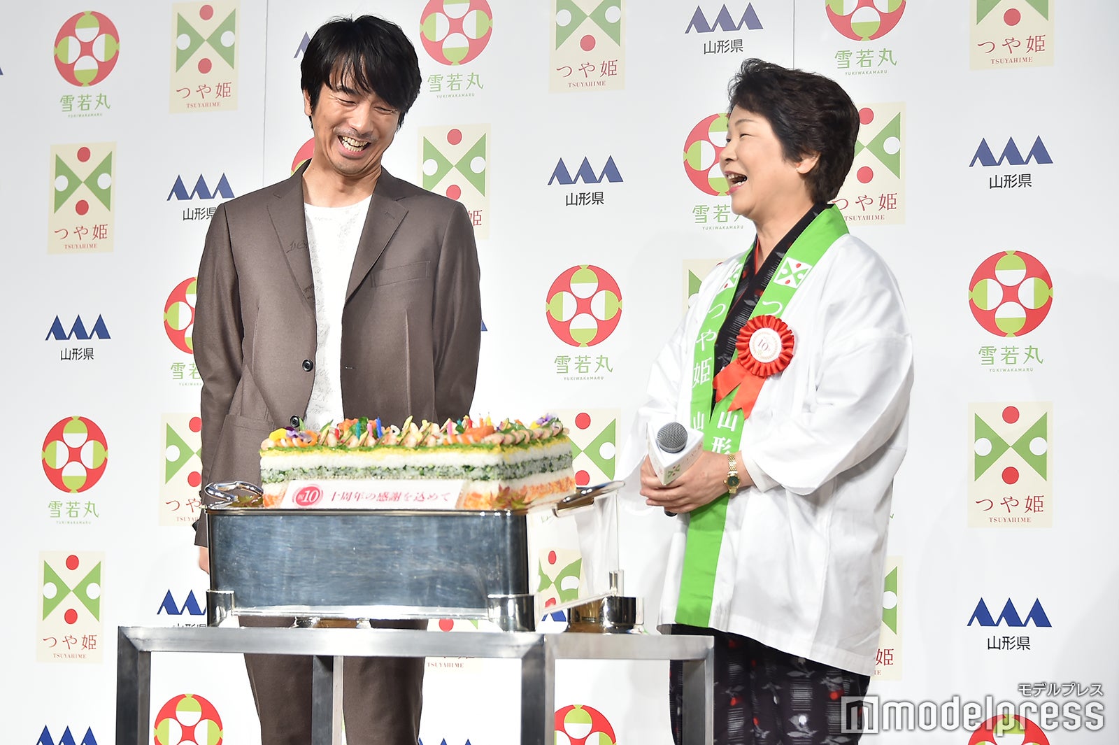 ろうそくの火を吹き消して照れ笑いを浮かべる眞島秀和、吉村美栄子県知事（C）モデルプレス