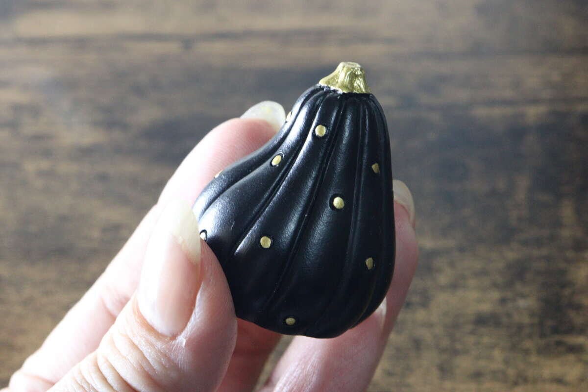 指でつまむように持たれた黒いかぼちゃ型オブジェ