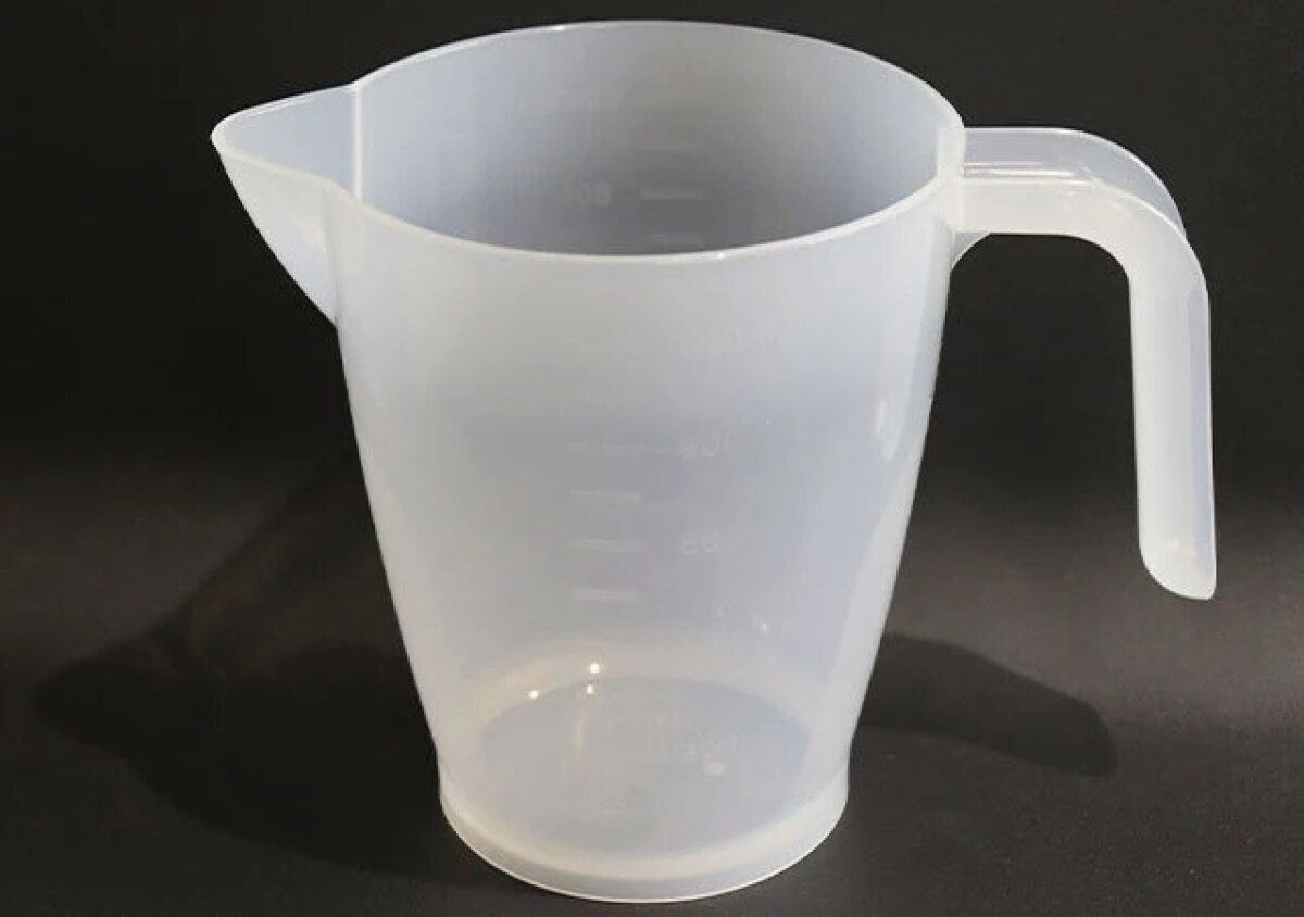 透明なプラスチック製の万能メジャーカップが黒い背景に置かれている 透明なプラスチック製の万能メジャーカップが黒い背景に置かれている
