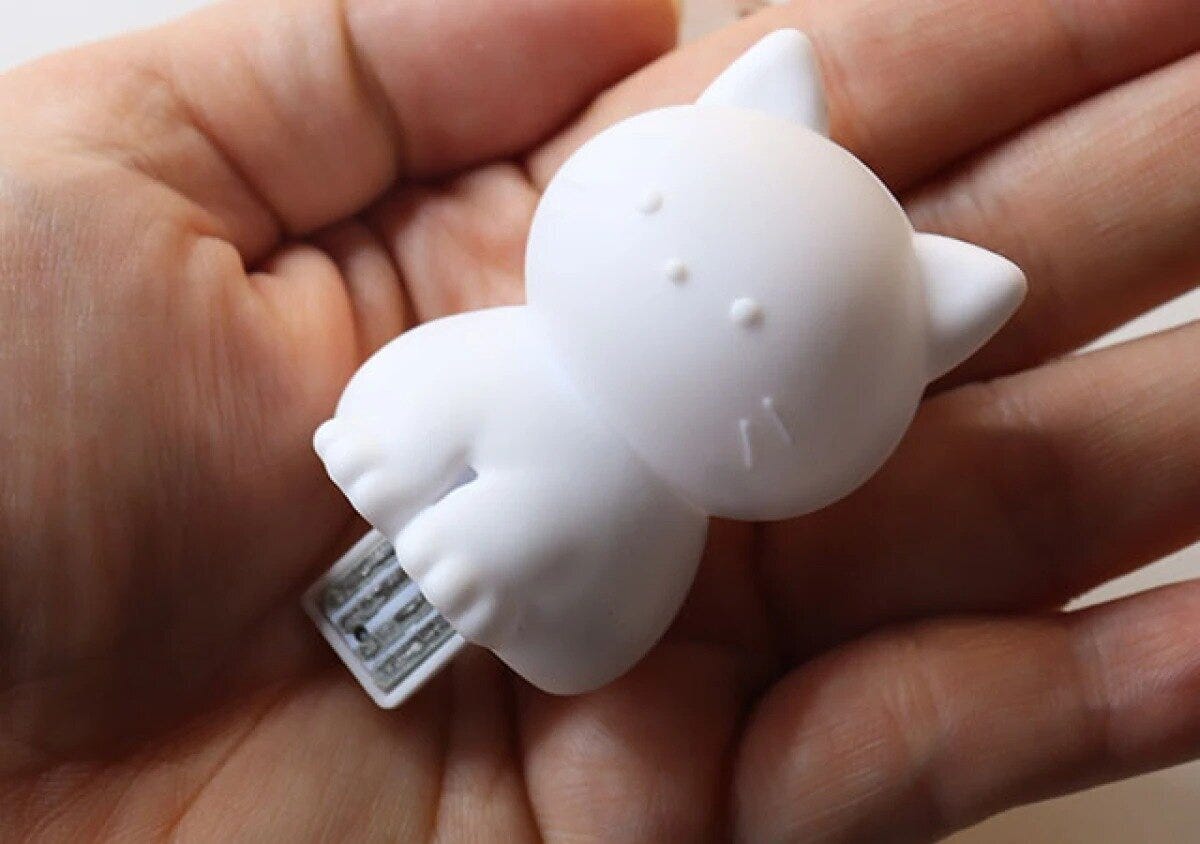手のひらに乗せた白い猫型ライト。USB端子が見える