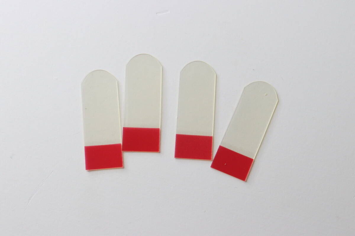 透明な伸びるテープ4枚が赤い保護フィルムを付けて並べられている