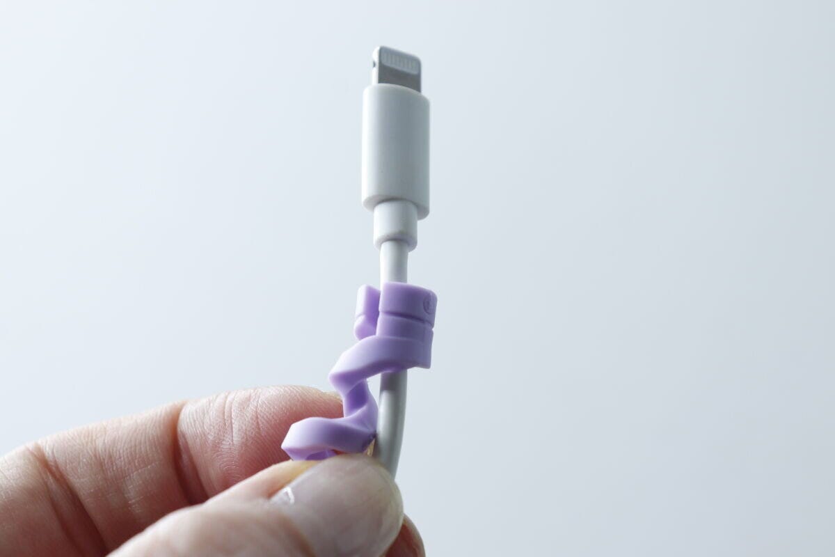 白い充電ケーブルの根元に紫のプロテクターを装着し始めた様子 白い充電ケーブルの根元に紫のプロテクターを装着し始めた様子