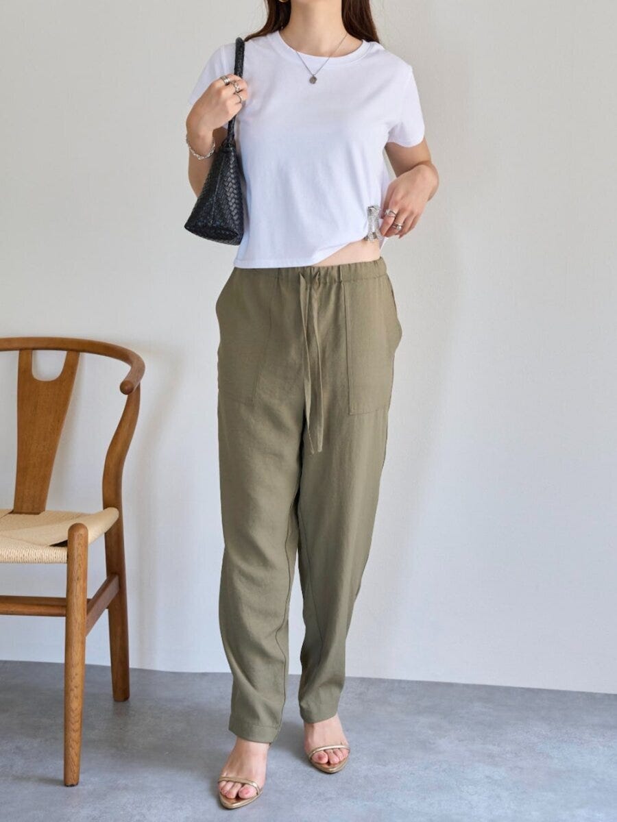 白Tにカーキのテーパードパンツを合わせ、黒バッグを持つ女性 白Tにカーキのテーパードパンツを合わせ、黒バッグを持つ女性